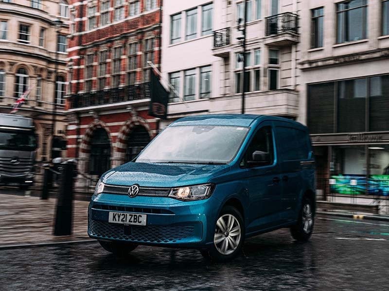 blue volkswagen caddy driving in a city