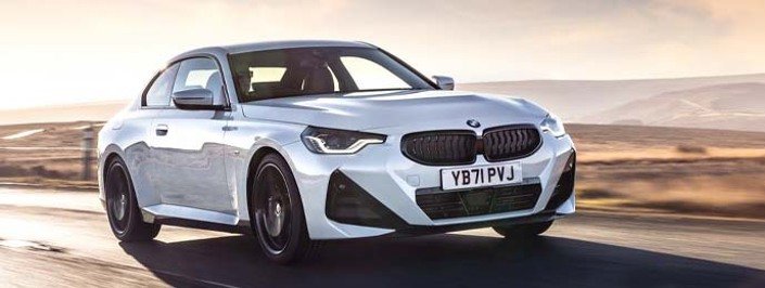 white bmw 2 series driving on the road