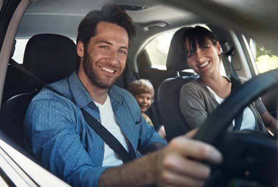 man, woman and child sat in a car smiling