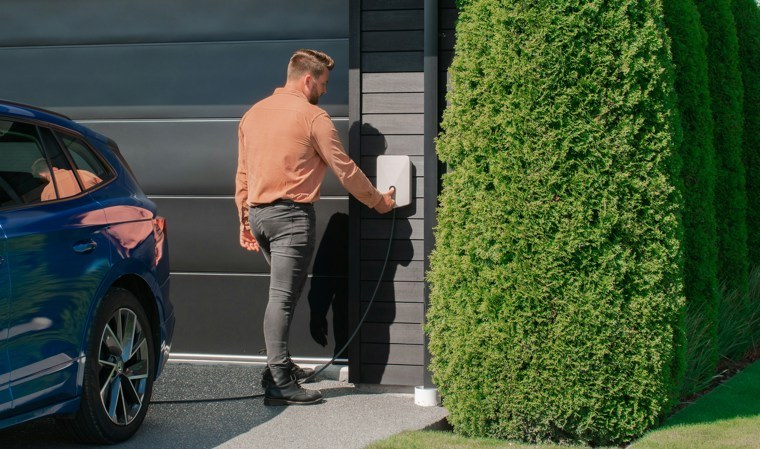 man using electric car charging point at home