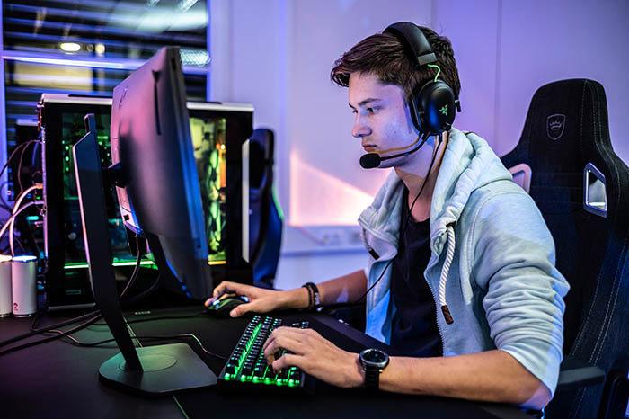 A gamer wearing a headset sitting in front of a computer