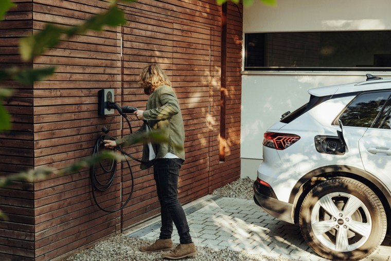 man using ev charger on a brick wall