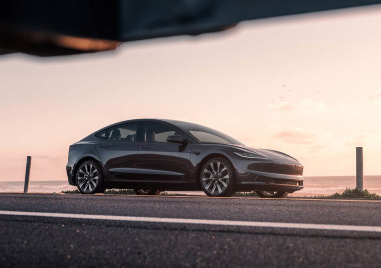 Tesla Model 3 parked on the road with sunset in background