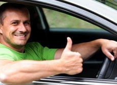 man driving car with thumbs up