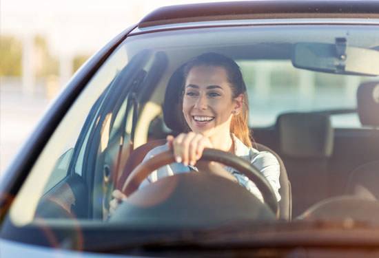 young woman smiling at wheel of hatchback car