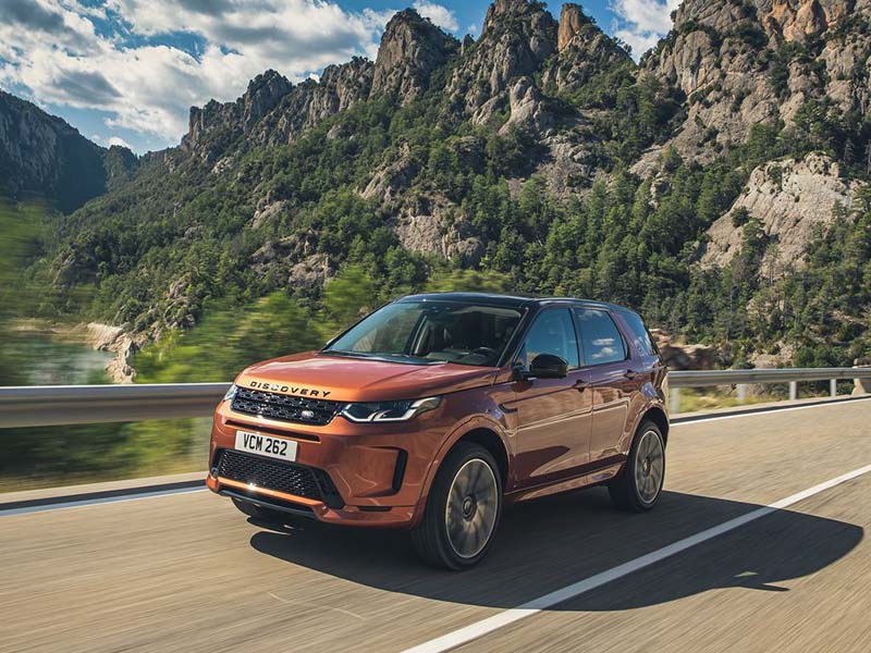 orange land rover discovery sport driving on country road