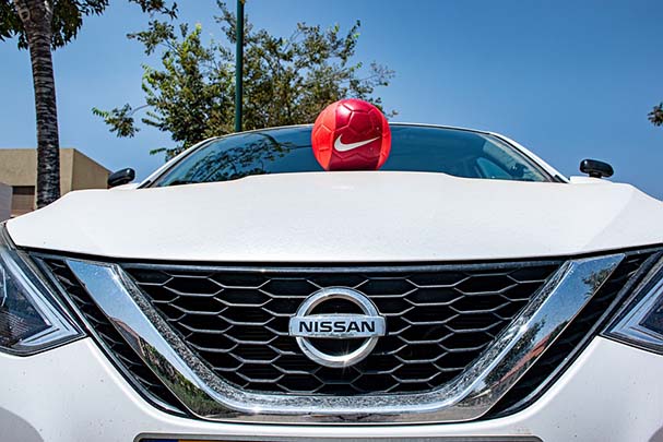 red football sat on the bonnet on a white nissan  