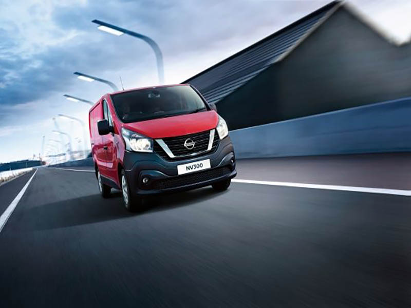 red nissan nv300 driving on road