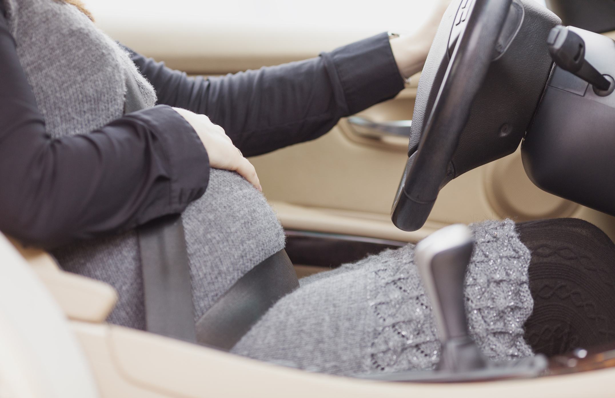 Pregnant woman sitting behind the wheel of a car