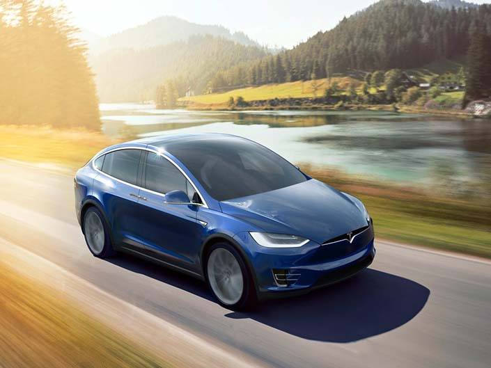 A blue Tesla Model X driving on the road