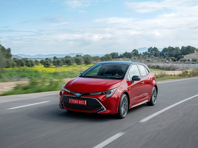 red toyota corolla hatchback driving on the road