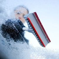 driver scrapping ice from car windscreen