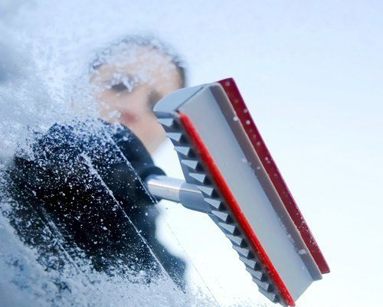 driver scrapping ice from car windscreen