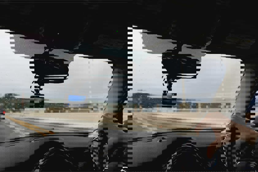 photo of a person driving with a dash cam in the windshield
