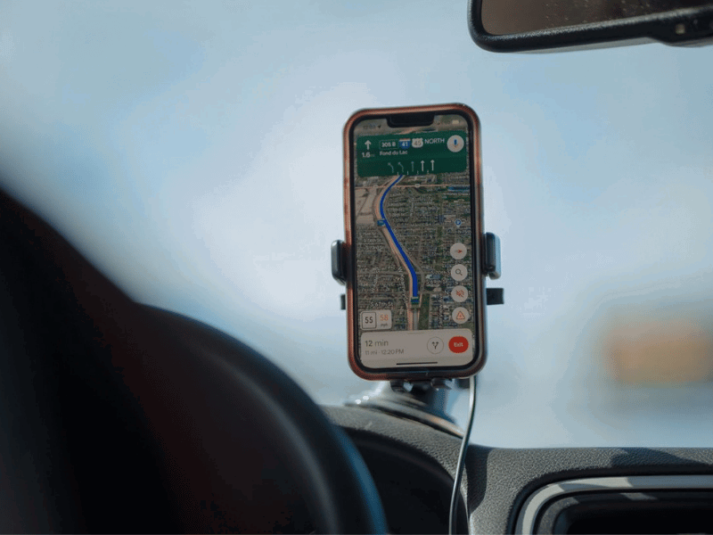 A smartphone with GPS navigation app mounted on a car dashboard during a road trip.