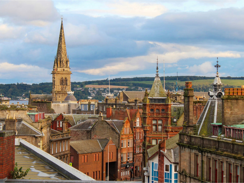 Skyline of a British town with a church spire in the middle and hills in the background