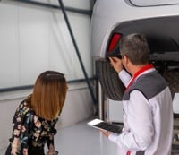 a man and woman looking under a car
