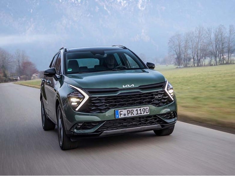 green kia sportage driving on the road
