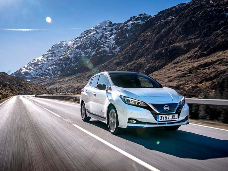 white nissan leaf driving through mountain range