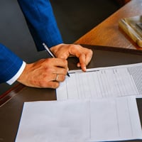 person writing on white form paper