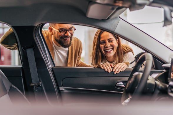A couple looking inside a new car at the dealership