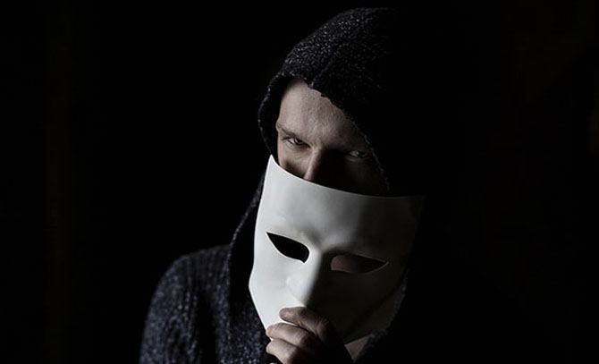 Close up of scammer hiding behind a mask.