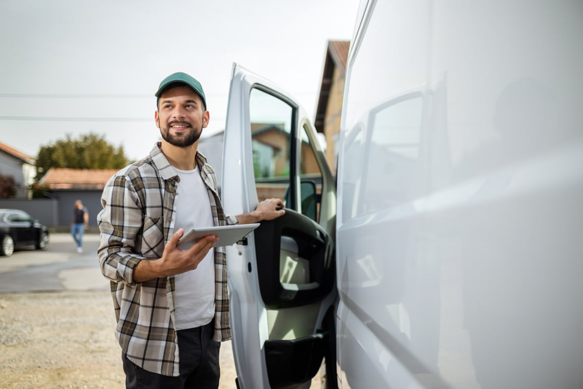 man stood next to van with ipad in his hands