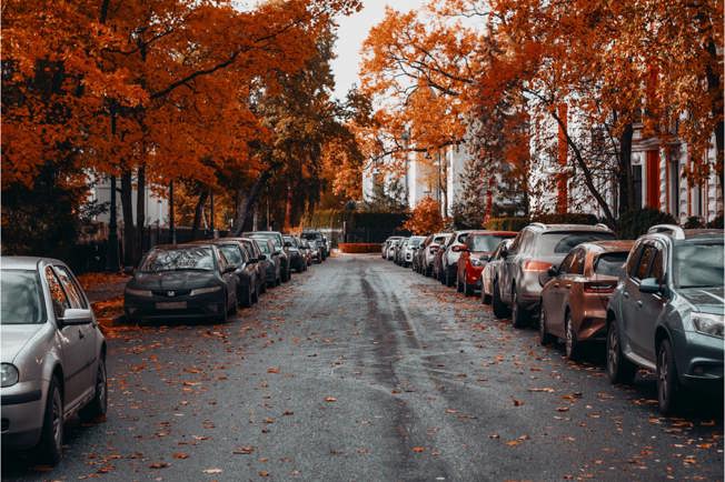 cars parked on the side of a suburban road during autumn