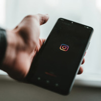 man holding mobile phone looking at instagram