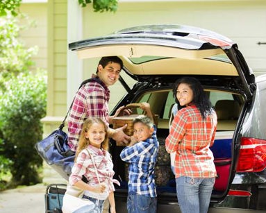 young family loading luggage into suv