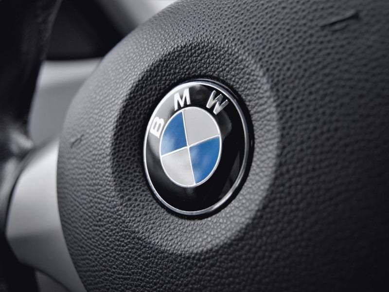 Detailed view of a BMW steering wheel with focus on the emblem showcasing luxury and design.
