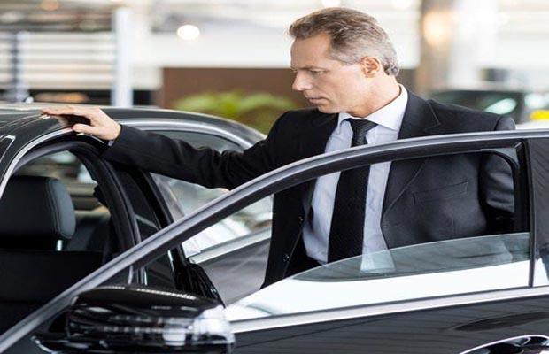 A businessman standing next to a car representing business leasing.