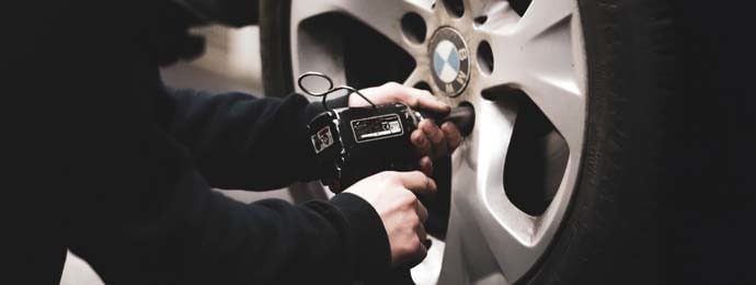man removing locking wheel nuts from car tyre