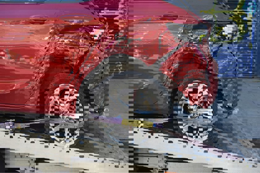 Damaged red car on a recovery truck