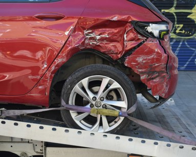 Damaged red car on a recovery truck