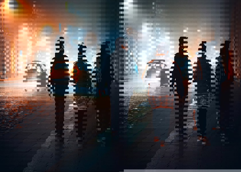 Three people walking alongside road at night