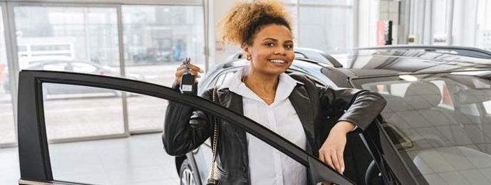 Woman in car showroom holding car keys