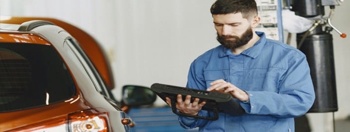 Mechanic checking the exterior of a car and using a tablet