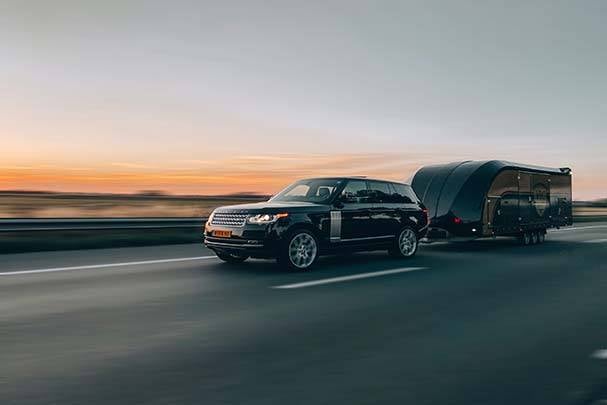A car towing a trailer on a road.