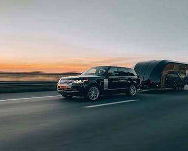 A car towing a trailer on a road.