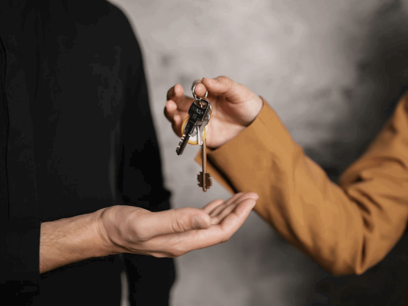 Detailed close-up of one person handing over keys to another, symbolizing a real estate transaction.
