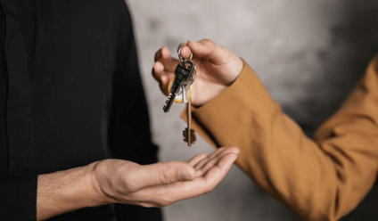 Detailed close-up of one person handing over keys to another, symbolizing a real estate transaction.