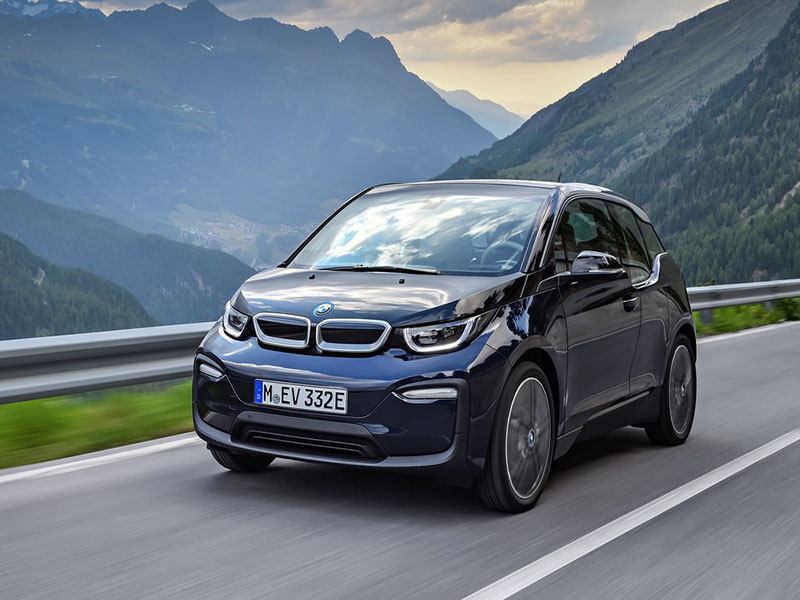 dark blue bmw i3 driving with mountains in the background
