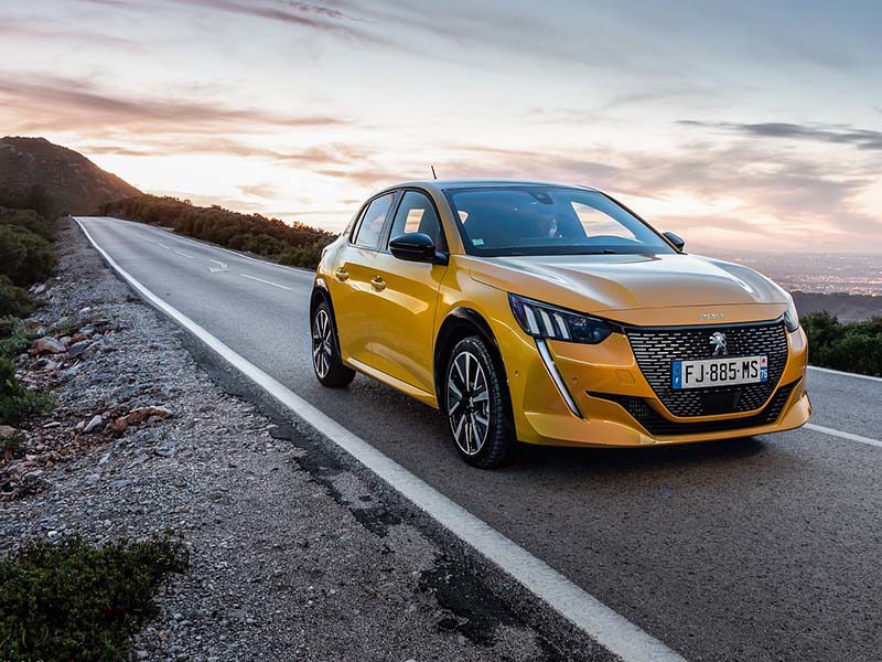 Yellow Peugeot 208 on country road at dusk