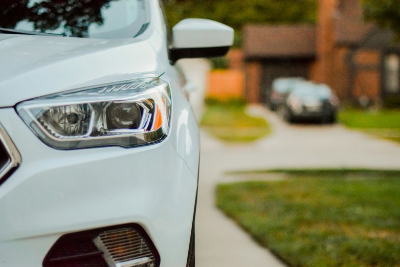 Close up of a white car parked on a driveway in an urban area