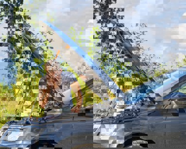 man on phone looking under car bonnet