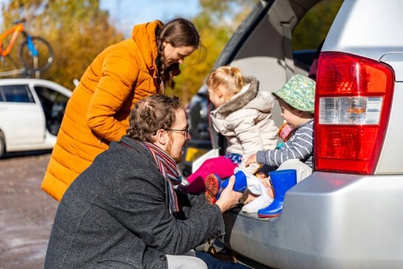 Family putting wellies on their children sat in the back of a car