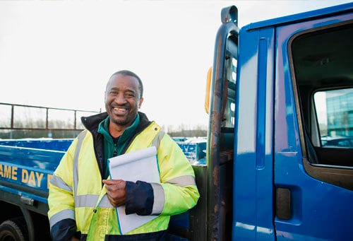 Portrait of a senior manual worker standing outside of his van with a clipboard.