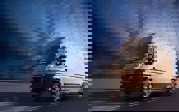 A commercial van driving over a suspension bridge.