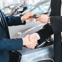 close up of hands shaking and exchanging car keys